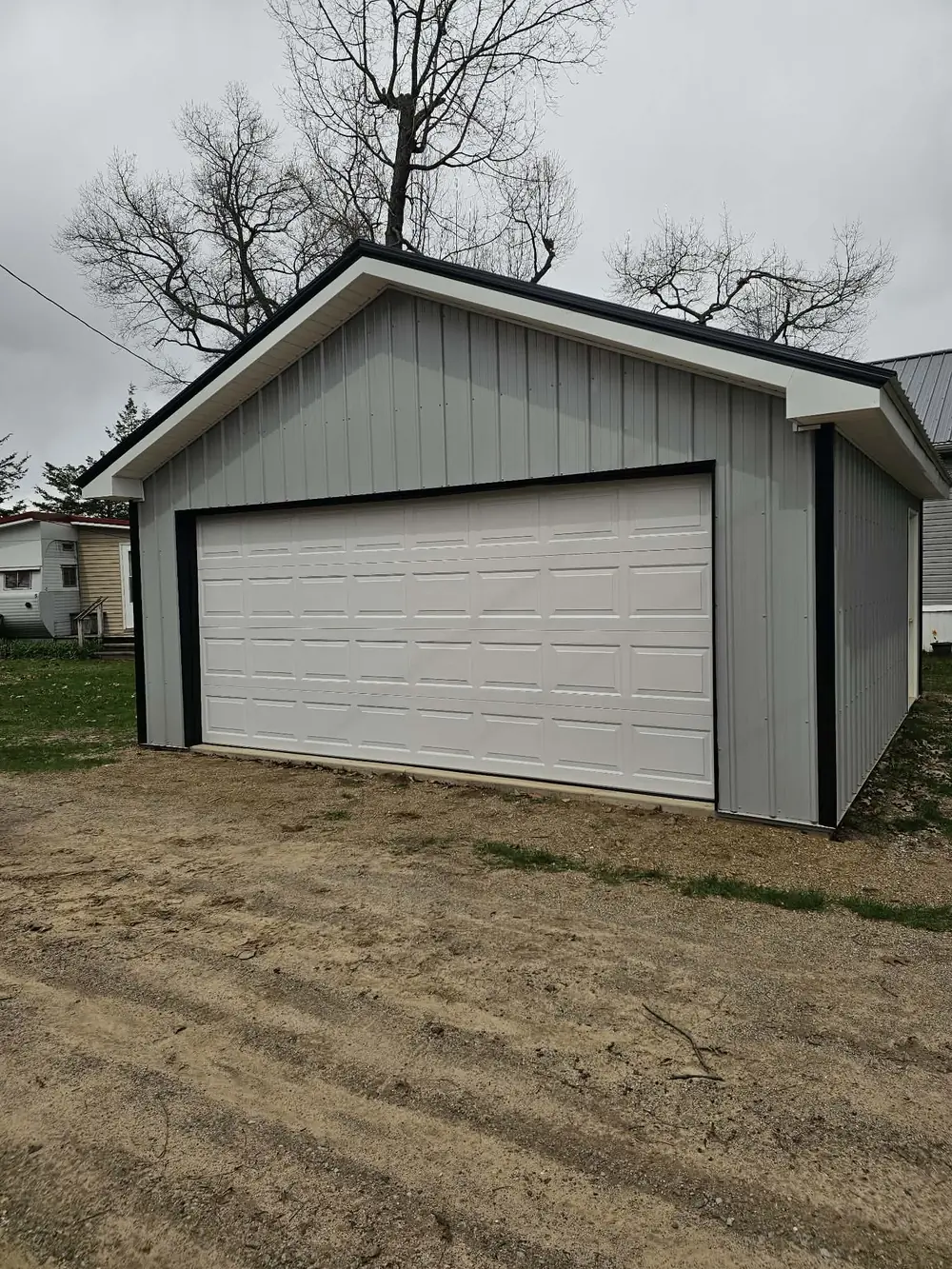 Completed detached metal garage with a white overhead door