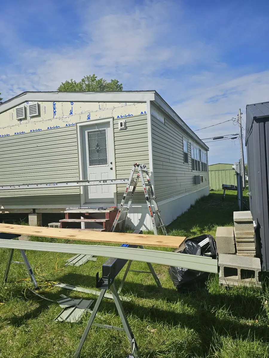 Exterior renovation in progress with house wrap and new windows