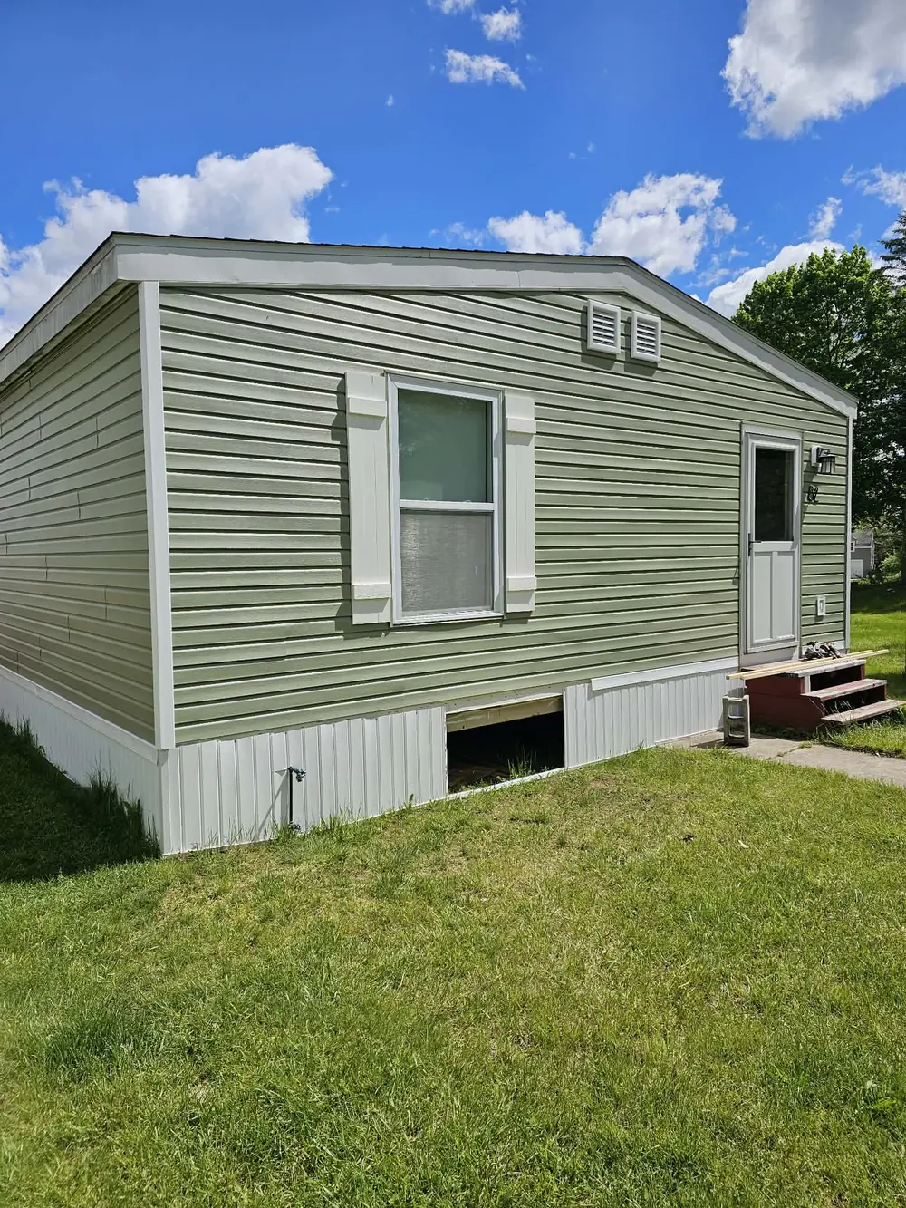 Completed green vinyl siding and white exterior trim on a manufactured home