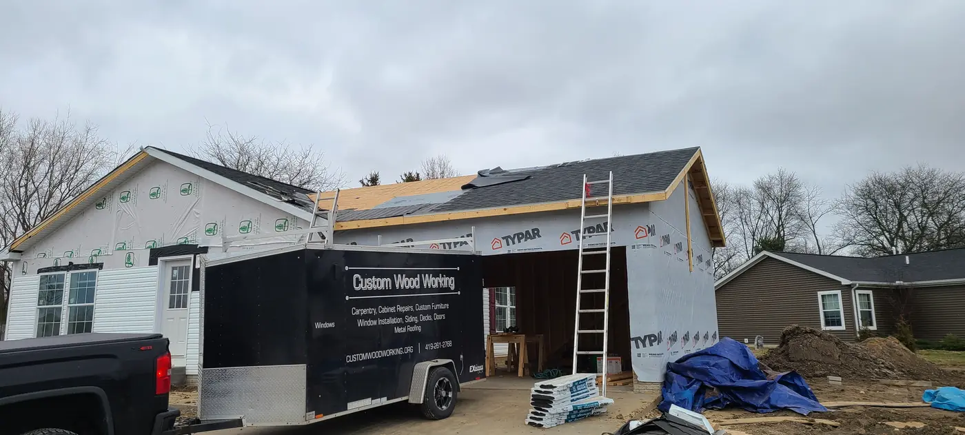Framed residential addition with roofing work underway